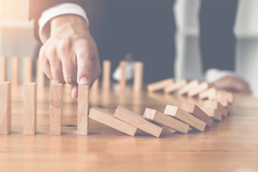 Man stopping a line of falling wooden dominos with his finger image, for Making a Will when you don't have children blog