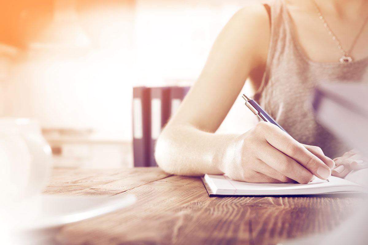 Woman sat at table wring in a notepad image for which type of will is right for you blog